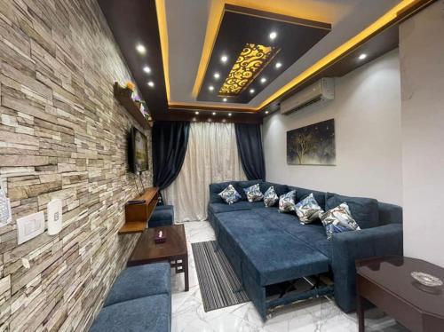 a living room with a blue couch and a brick wall at Porto said بورتوسعيد شاليه غرفه وصاله للأسر فقط in `Ezbet Shalabi el-Rûdi