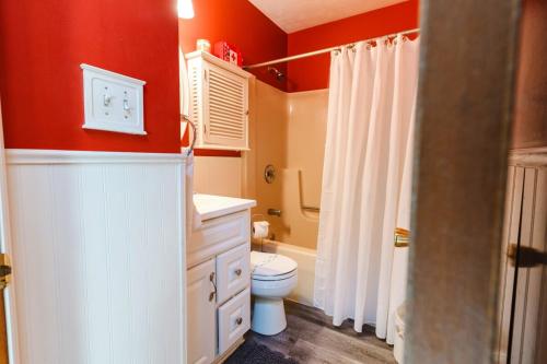 a bathroom with a white toilet and a red wall at The CubHouse Poconos getaway in Tobyhanna