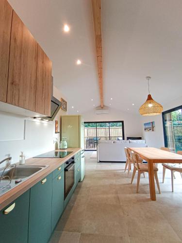 une cuisine avec des armoires bleues et une table ainsi qu'une salle à manger dans l'établissement Villa MACAO, à Gujan-Mestras