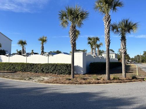 a street with palm trees in front of a white fence at NEW Pool 4 BDR Golf Cart in Inlet Beach
