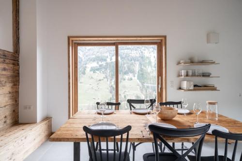 a dining room table with chairs and a large window at La ferme d'Hauteluce - Chalets in Hauteluce