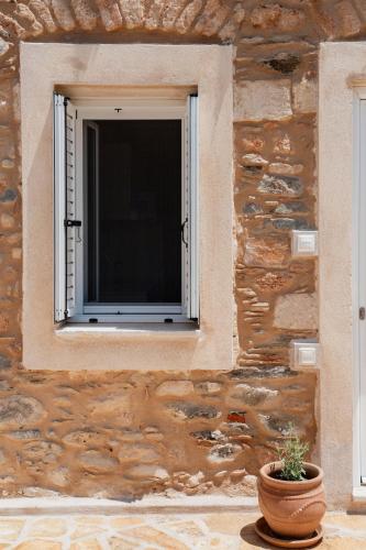a window on a stone wall with a potted plant at Neapolis Oasis - Lower House in Neapolis