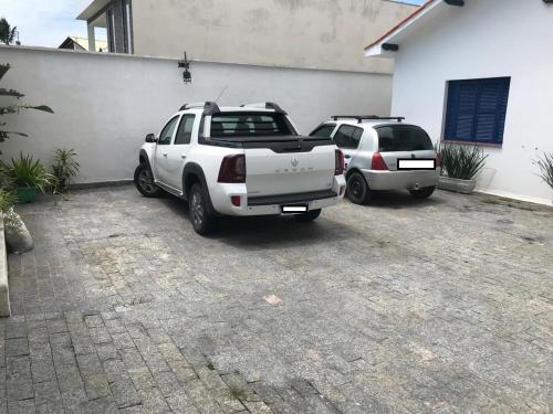 two cars parked in a parking lot next to a building at Kitnets a 200 m da praia in Peruíbe