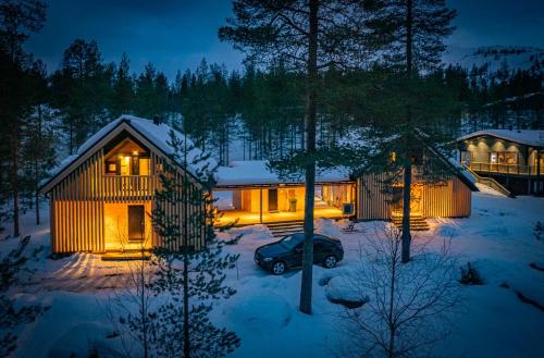 a house with a car parked in the snow at night at Kimmelvilla - Wilderness in your living room in Pyhätunturi