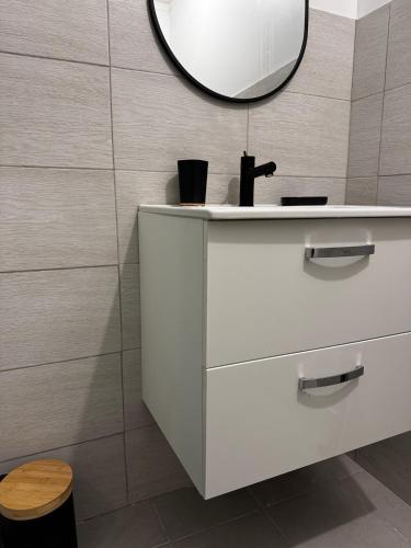 une salle de bain avec un lavabo blanc et un miroir dans l'établissement Petit appt cosy et moderne, à Perpignan