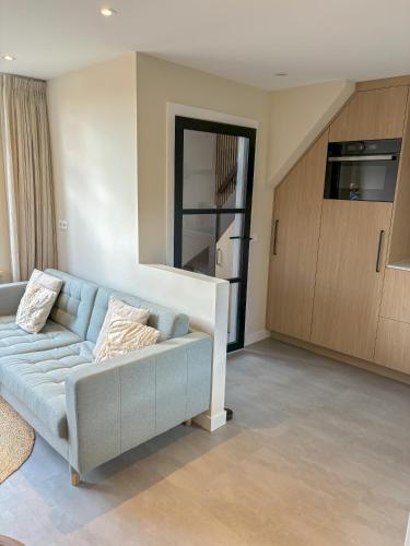a living room with a blue couch and a kitchen at Casa Bon Bini in Egmond aan Zee