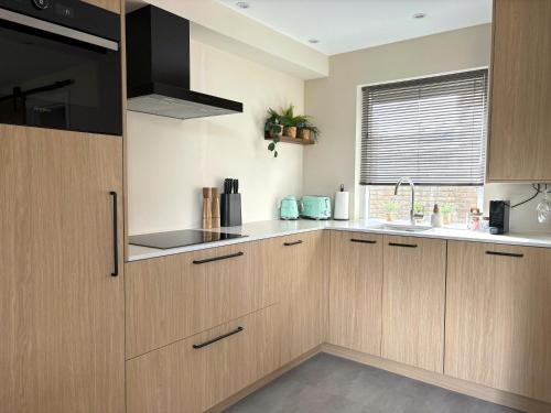 a kitchen with wooden cabinets and a sink at Casa Bon Bini in Egmond aan Zee