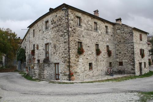 ein altes Steingebäude mit Blumen an den Fenstern in der Unterkunft Agriturismo Il Casalone in Badia Tedalda