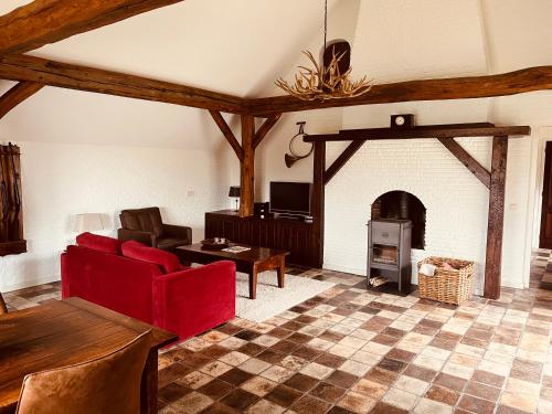 a living room with a red couch and a fireplace at Het Jachthuis Udenhout in Udenhout