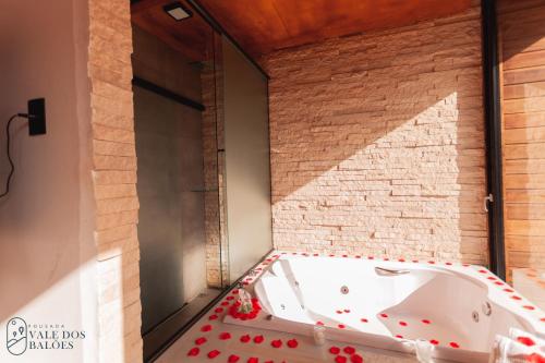 a bath tub in a room with a brick wall at Pousada Vale dos Balões in Praia Grande
