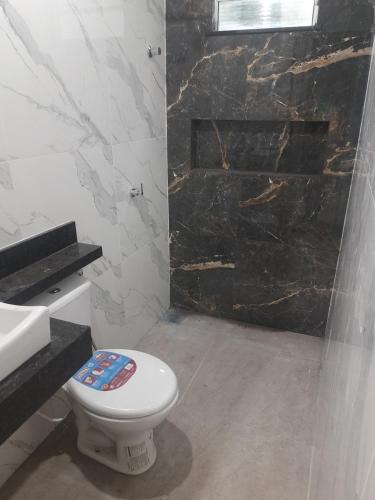 a bathroom with a toilet and a stone fireplace at COP 30 - Quarto privativo em casa com 3 quartos e 4 banheiros in Ananindeua