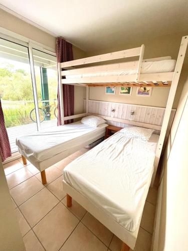 deux lits superposés dans une chambre avec fenêtre dans l'établissement Appartement en résidence, à Moliets-et-Maa