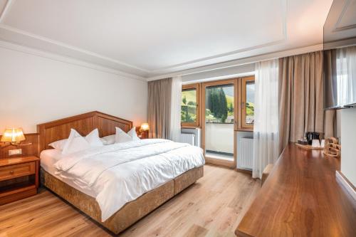 a bedroom with a large bed and a large window at Hotel Sun Valley in Selva di Val Gardena