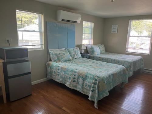 a bedroom with two beds and a tv and windows at Pine View Lodge Old Orchard Beach in Old Orchard Beach