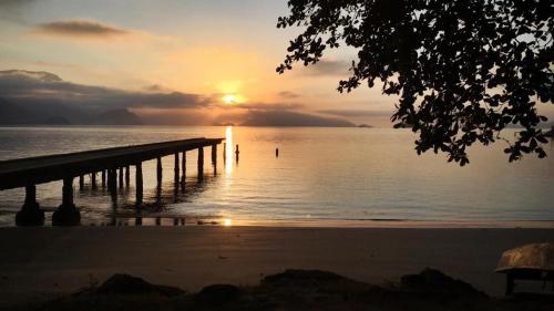 a sunset over the ocean with a pier at Pousada Costa dos Corais in Mangaratiba