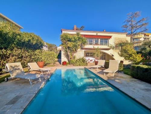 une piscine avec des chaises et une maison dans l'établissement Villa bagatelle Cimiez, à Nice