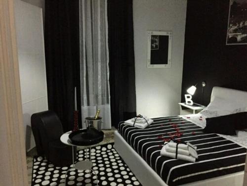 a black and white bedroom with a bed and a chair at Alba Camere in Palermo