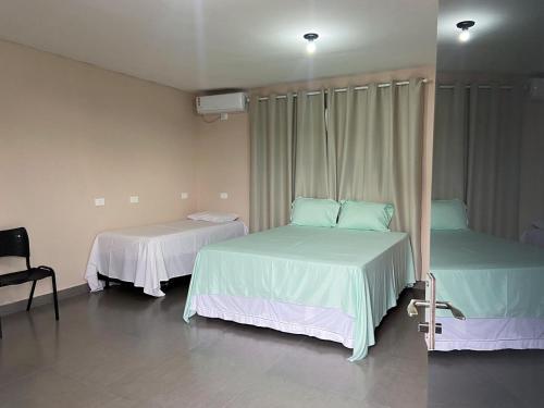 a room with two beds and a chair at Quartos a 1km do centro de Pirenópolis in Pirenópolis