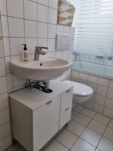 a white bathroom with a sink and a toilet at Tischfussball Quartier Köln-Niehl in Cologne