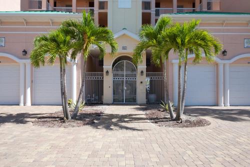two palm trees in front of a building with a gate at Palm Harbor #403 by Sun Palace Vacations in Fort Myers Beach