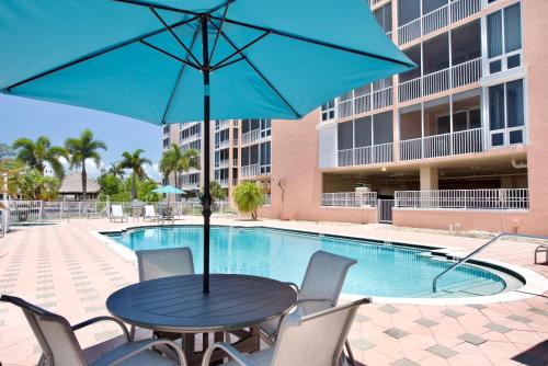 a table and chairs with an umbrella next to a pool at Palm Harbor #403 by Sun Palace Vacations in Fort Myers Beach