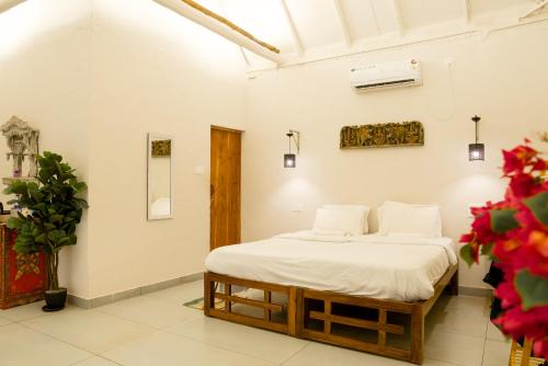 a bedroom with a bed in a white room at Nidra by Sarwaa in Varkala