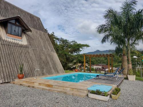 een zwembad met een houten terras naast een huis bij Chalé Bem-Estar in Massaranduba
