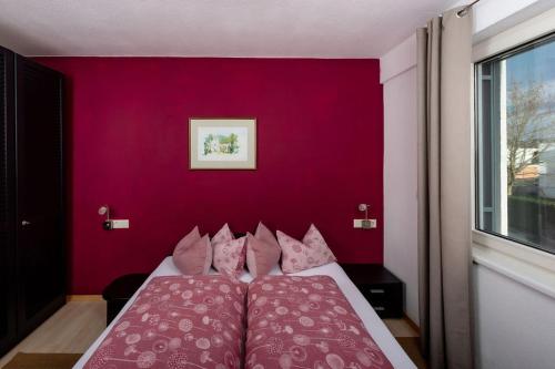 a bedroom with a red wall with a bed with pink pillows at Ferien im Paradies - Wohnung Vera in Höchst
