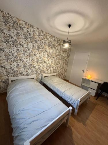 deux lits dans une chambre avec un mur dans l'établissement T3 centre ville Rodez, à Rodez