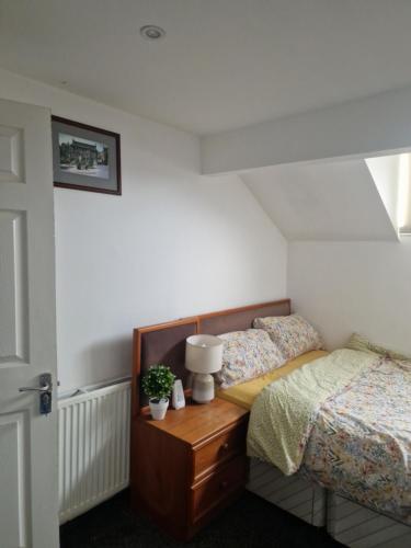 Un dormitorio con dos camas y una mesa con lámpara. en En-Suite Double Room in Haughton Green Denton M34, en Haughton Green