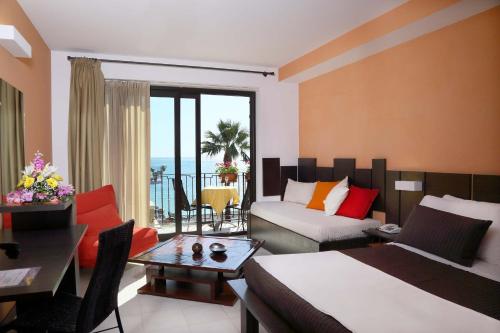 ジャルディーニ・ナクソスにあるHotel San Giovanniのベッドとリビングルームが備わるホテルルームです。
