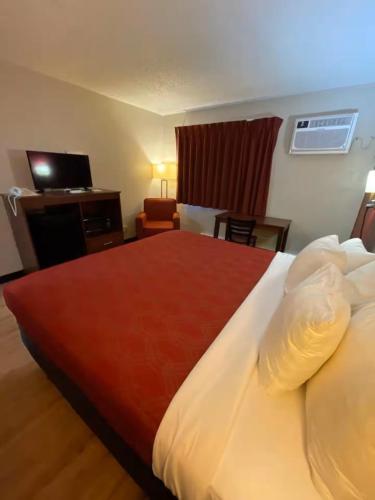 a hotel room with a large bed and a chair at High Desert Inn in Prineville