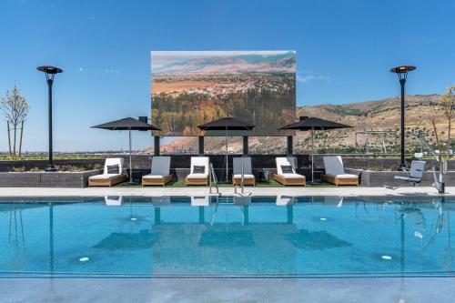 a pool with chairs and umbrellas and a large screen at Top floor Deluxe 1BR Pool,Gym,Htub,Bowling and More in Salt Lake City