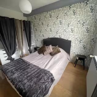 - une chambre avec un grand lit dans une pièce avec du papier peint dans l'établissement Le Presbytère Normand, à Canapville