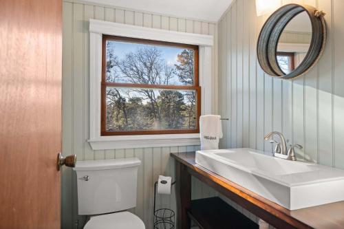 a bathroom with a white sink and a window at Unique A Frame Short Drive to Beach in Barnstable
