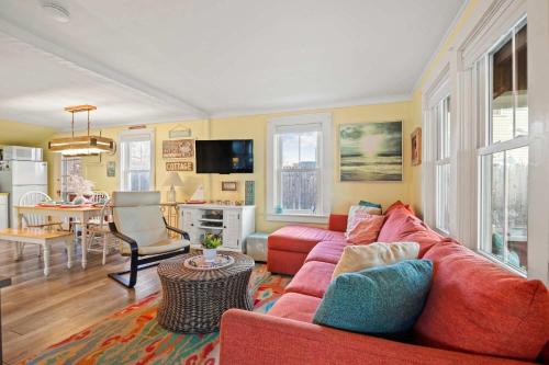 a living room with a red couch and a kitchen at Walk to Private Bayside Beach in Brewster