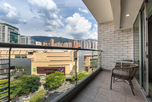 a balcony with a chair and a view of a city at Estelar Apartamentos Medellin in Medellín