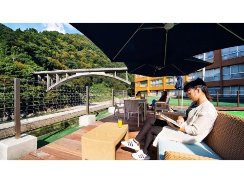 a woman sitting on a bench under an umbrella at Togen Kurobe UnazukiOnsen - Vacation STAY 04361v in Kurobe