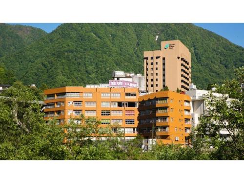 a tall building in front of a mountain at Togen Kurobe UnazukiOnsen - Vacation STAY 04361v in Kurobe