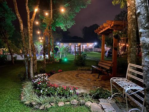 a park at night with a bench and flowers at Casa de campo com piscina em meio à natureza in Campo Magro