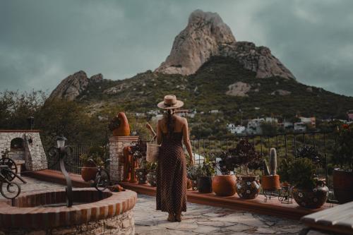 a woman in a hat standing in front of a mountain at El Cantar del Viento- Hotel Boutique in Bernal