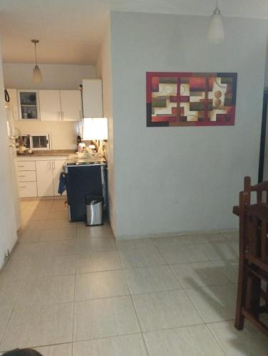 Una cocina con gabinetes blancos y piso de baldosas. en Casa con pileta, en La Rioja