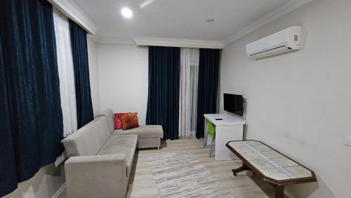 a living room with a couch and a tv at KARTALKAYA APART OTEL in Antalya