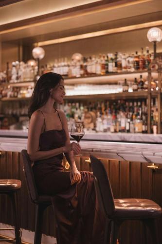 a woman sitting in a chair holding a glass of wine at The Ritz-Carlton, Boston in Boston