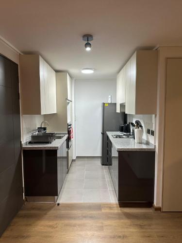 a kitchen with white cabinets and black appliances at Amplio departamento en zona céntrica de Concepción in Concepción