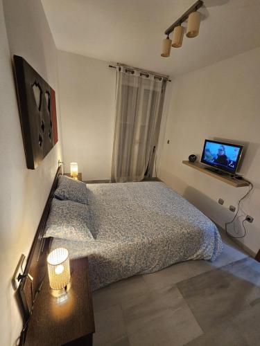 a bedroom with a bed and a tv on the wall at Apartamento Elegance Benidorm in Villajoyosa