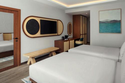 a bedroom with two beds and a tv on the wall at The Isolano, Adults Friendly Resort, Autograph Collection - 12years and above in Cres