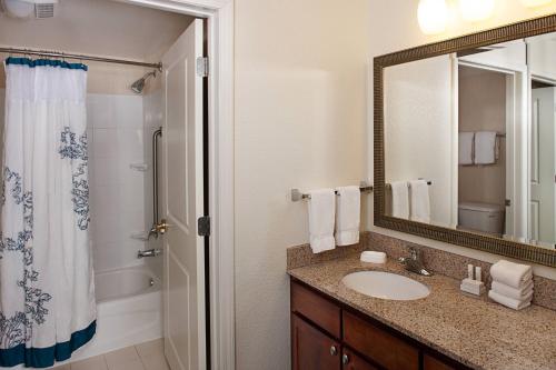 a bathroom with a sink and a shower and a mirror at Residence Inn Long Island Holtsville in Holtsville