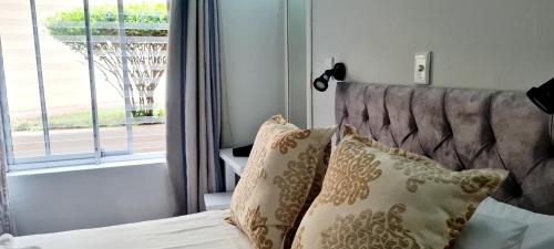 a bedroom with a bed with pillows and a window at Chakas Rock Beach Chalet 32 in Ballito