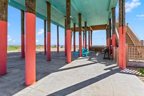a building with orange columns on the beach at Beachfront HotTub Gameroom CargoLift - SandyCheeks in Bolivar Peninsula